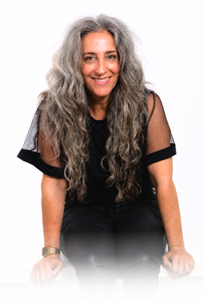 Rocío Torres sonriendo, sentada sobre un banco blanco con fondo blanco, retrato profesional utilizado en la página Sobre Mí.