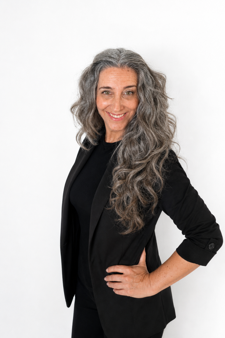 Rocío Torres, formadora profesional de uñas con más de 20 años de experiencia, sonriendo con blazer negro sobre fondo blanco.